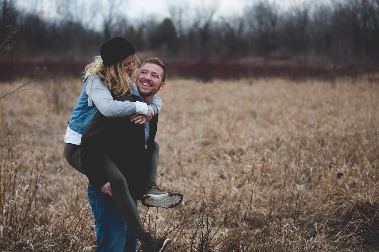 services-02 A happy couple enjoys a playful moment in a field during the day, symbolizing love and joy.